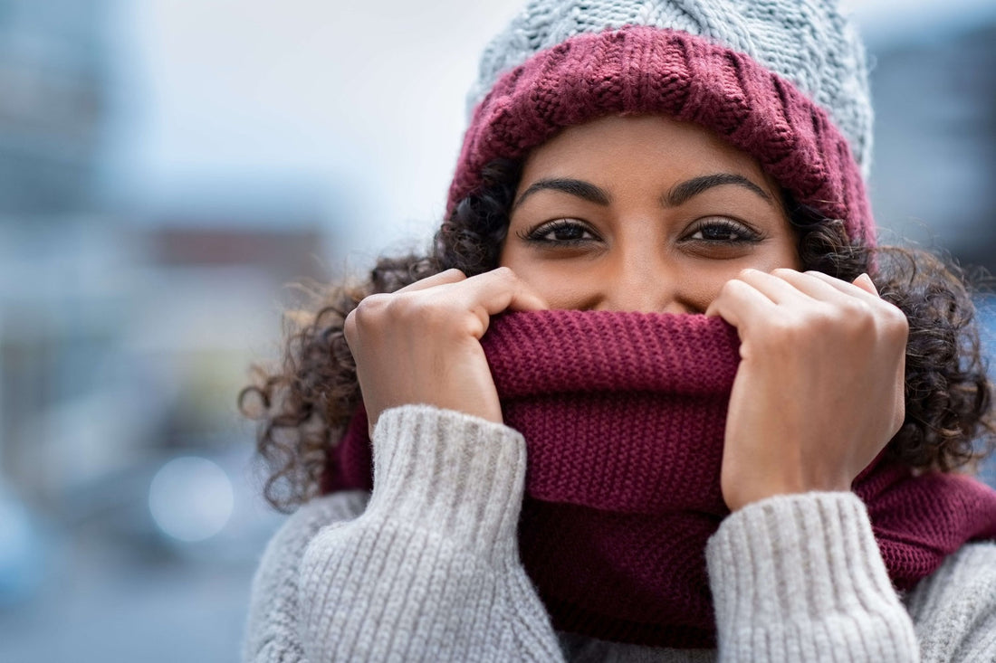 Woman pulling burgundy scarf over her face